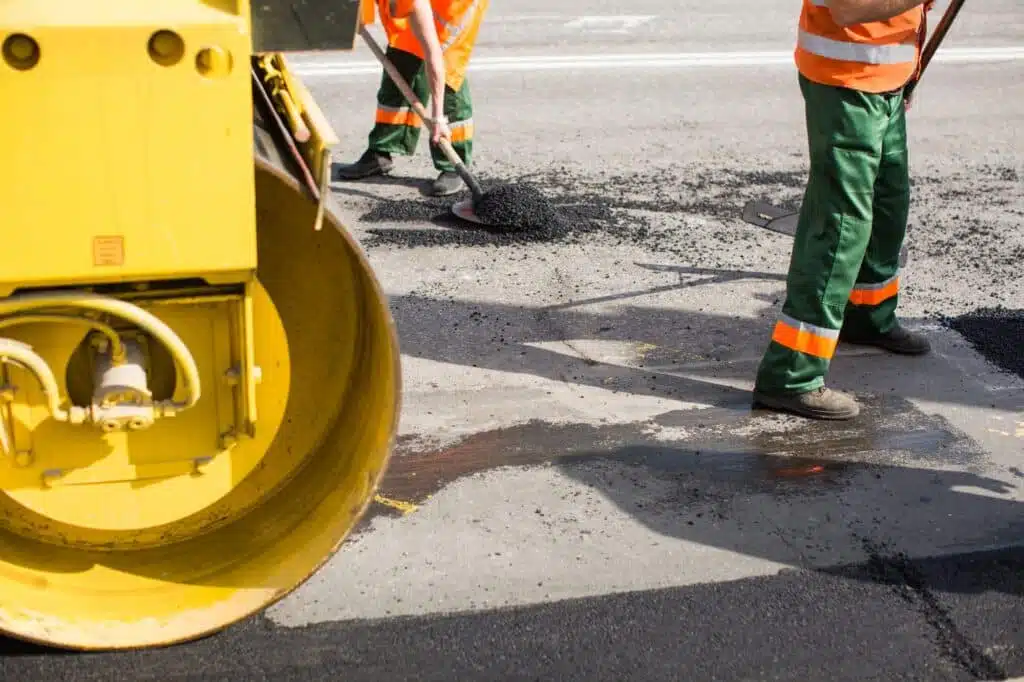 Workers on Asphalting paver machine during Road street repairing works. Street resurfacing.